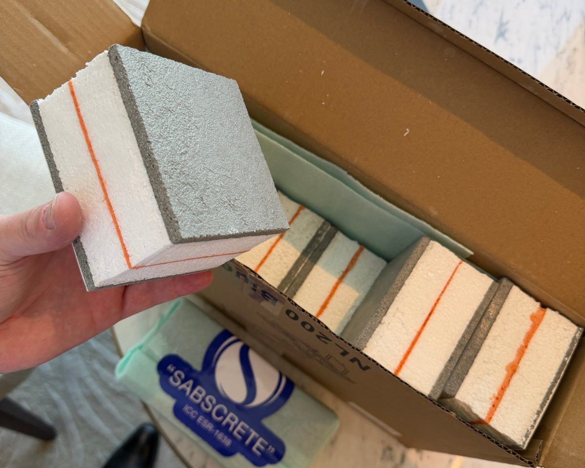 A SABS cube sample: grey SABScrete faces, white EPS foam and an orange lamination line