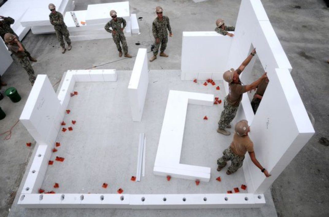 U.S. Navy Seabees standing up precut SABS foam walls on a slab