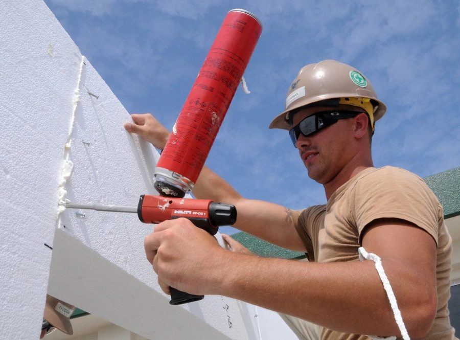 A Seabee bonding foam panels with a PU adhesive gun
